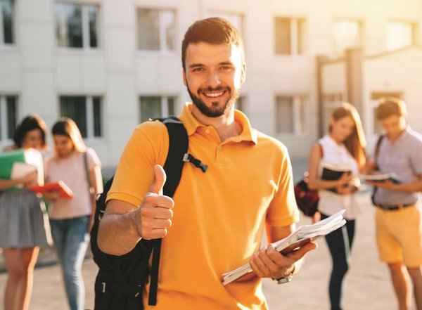 young_attractive_smiling_student_showing_thumb_up_outdoors_campus_university